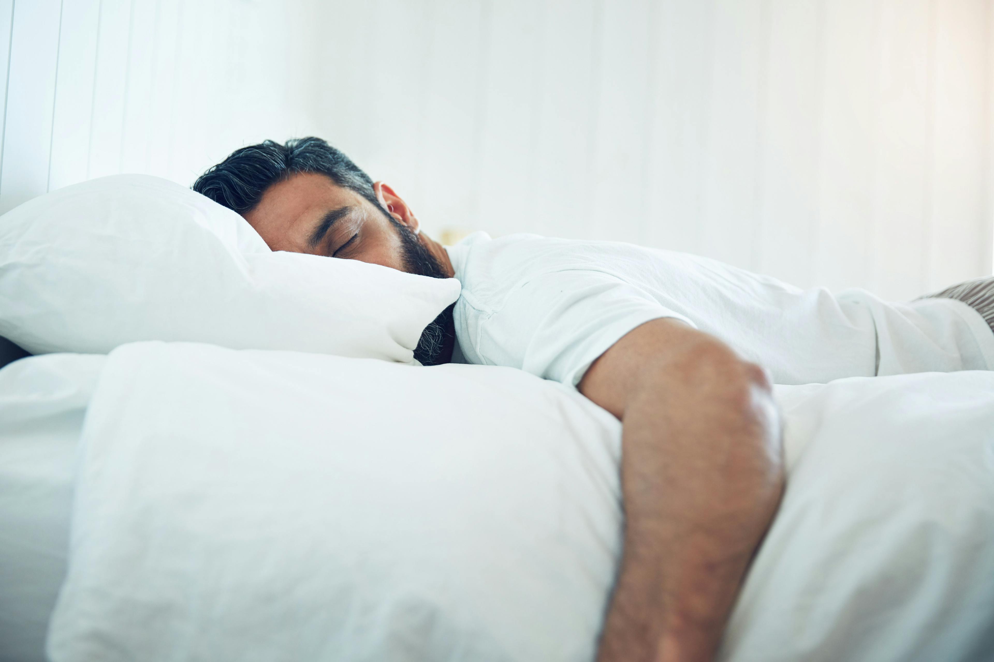 Tired, relax and a man on a bed for sleep, depression and fatigue at home. Rest, napping and a guy sleeping in the bedroom with insomnia, narcolepsy or depressed while lying looking exhausted.Image credit: Laflor/peopleimages.com | stock.adobe.com